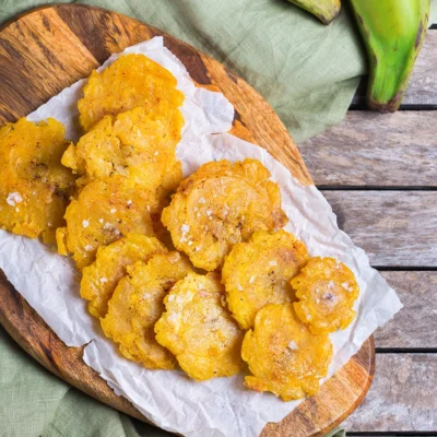 Beignets de plantain vert frits (plantain ferme non sucré) dorés et croustillants sur planche en bois