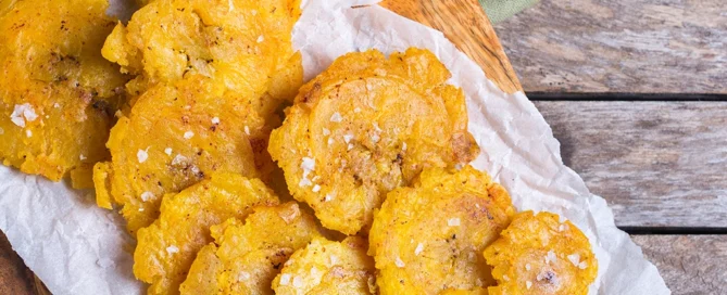 Beignets de plantain vert frits (plantain ferme non sucré) dorés et croustillants sur planche en bois
