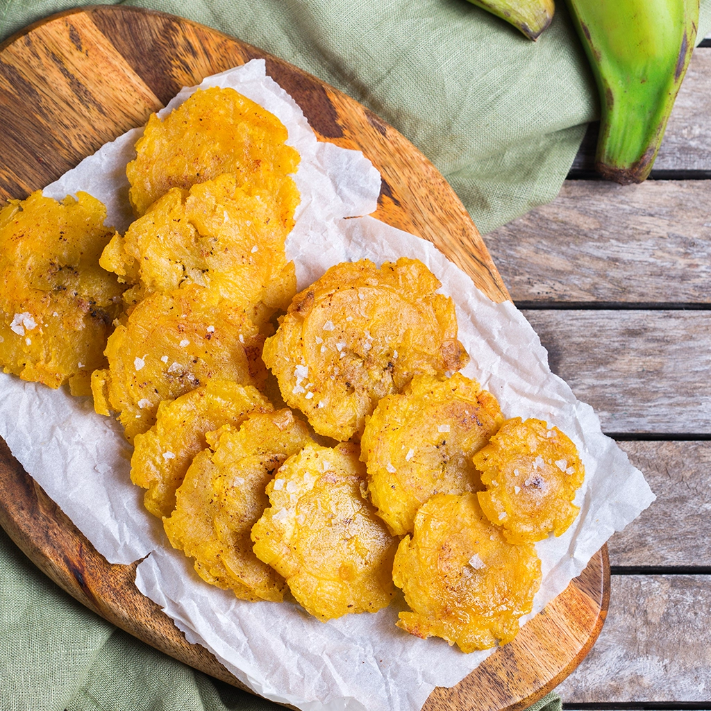 Beignets de plantain vert frits (plantain ferme non sucré) dorés et croustillants sur planche en bois