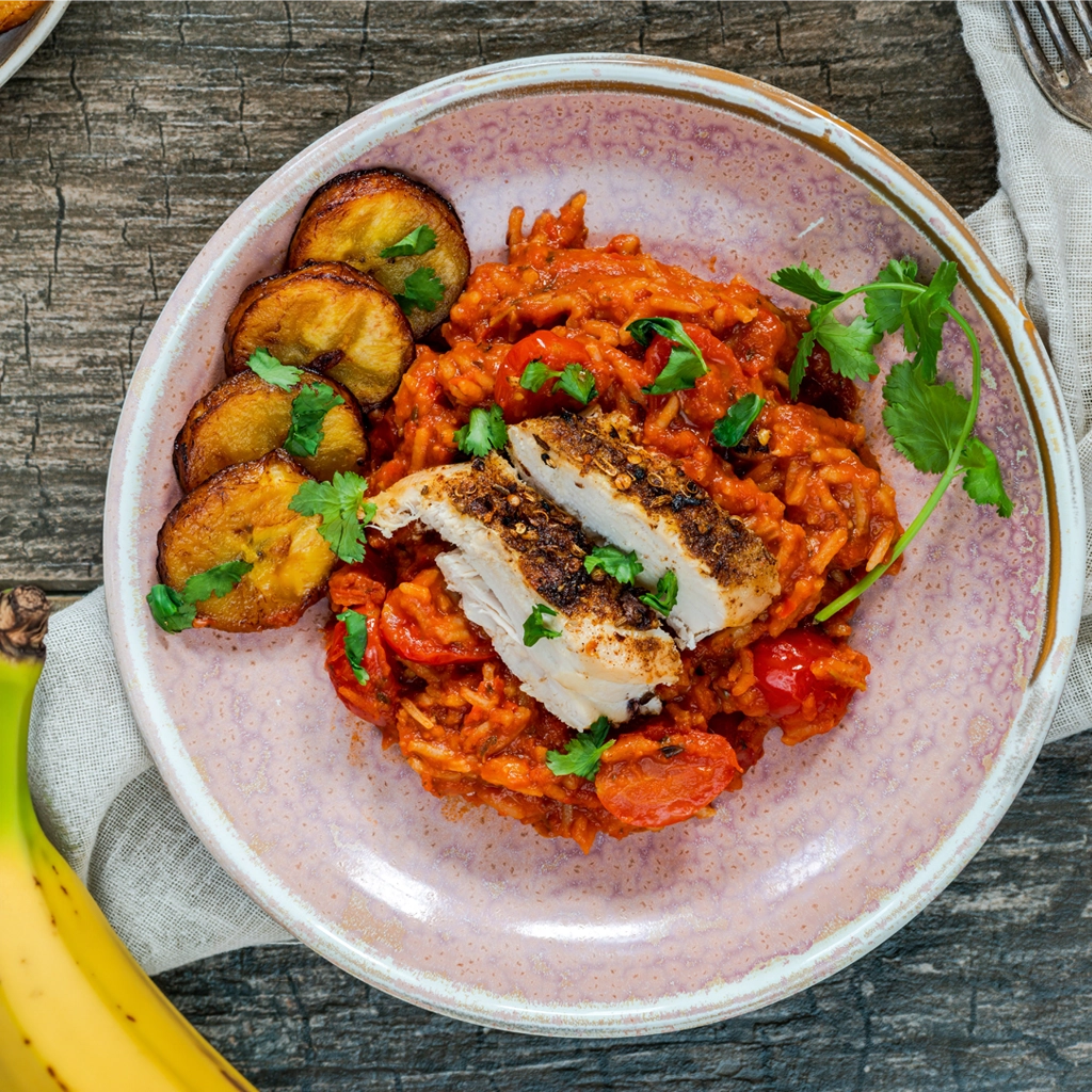Rondelles de plantain jaune frites servies avec riz en sauce tomate et poulet grillé, plantain mûr légèrement sucré